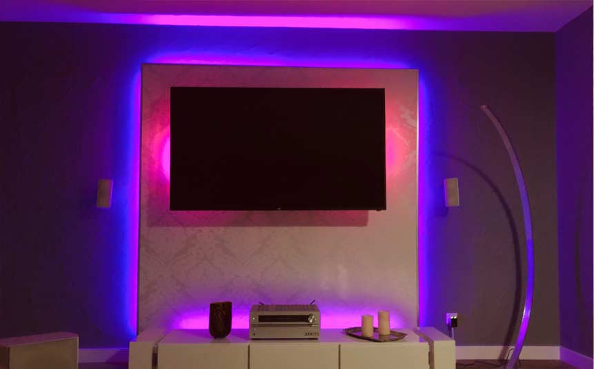 Smart LED light strips installed behind a TV in a bedroom